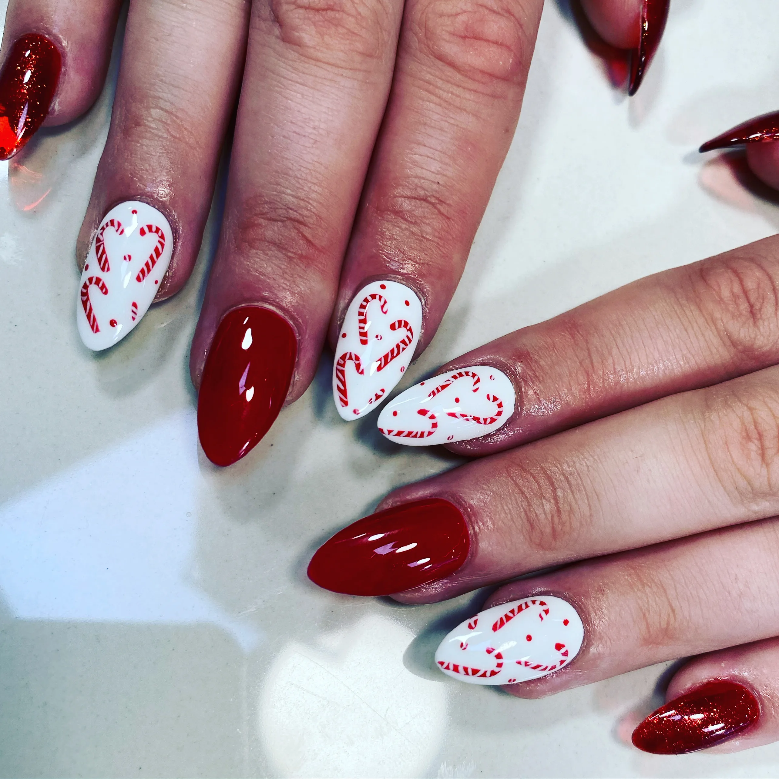 Red and white candy-cane heart Christmas nail art, almond shape