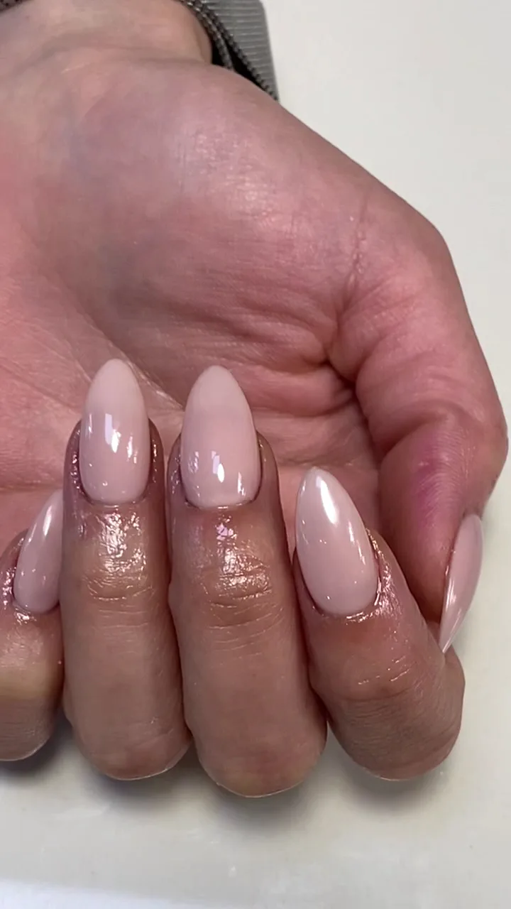 Single hand with milky nude almond gel nails, minimal and clean