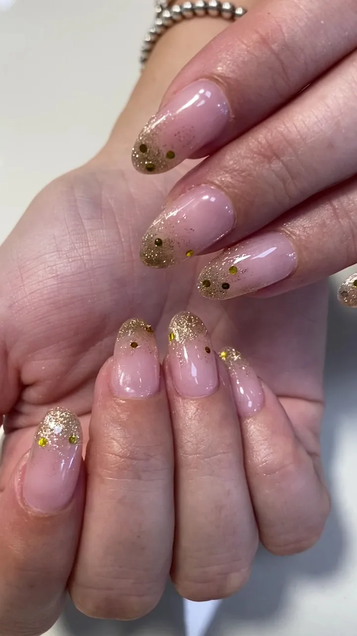 Hot pink nails with one gold-glitter accent on a sequin clutch